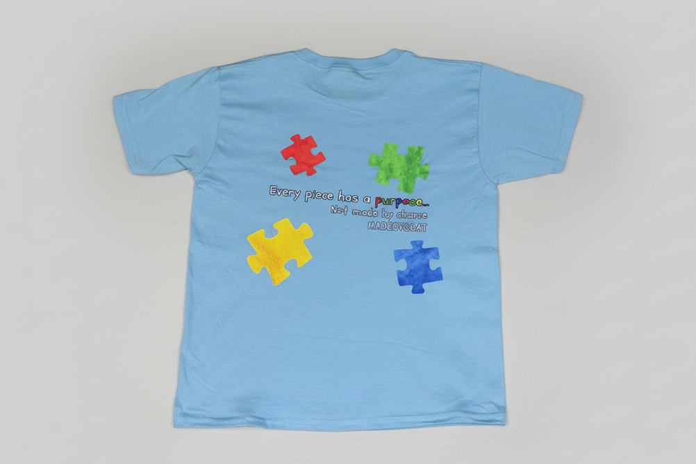 Light blue t-shirt with colorful puzzle pieces and text on a white background