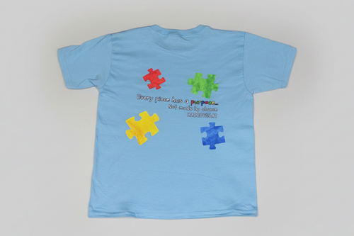 Light blue t-shirt with colorful puzzle pieces and text on a white background